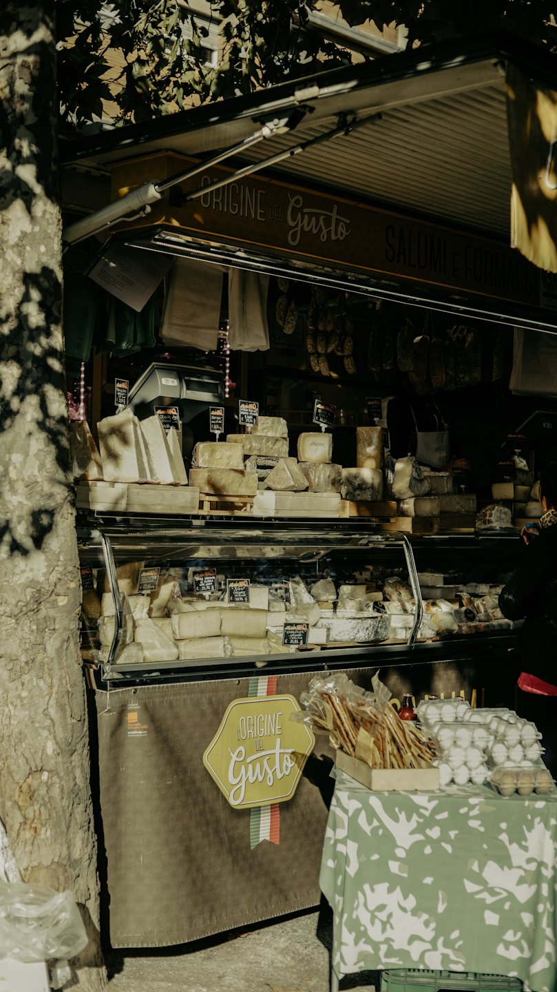 Formaggi artigianali e salumi in un mercato all'aperto.