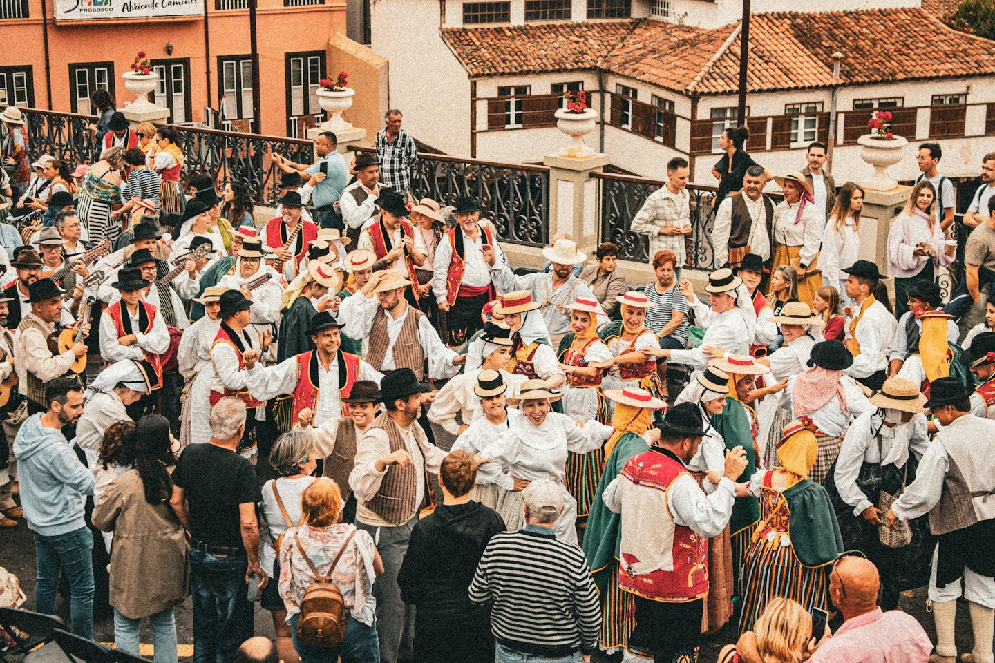 Una folla a una festa di paese in costume tradizionale con strumenti a corda e danze.