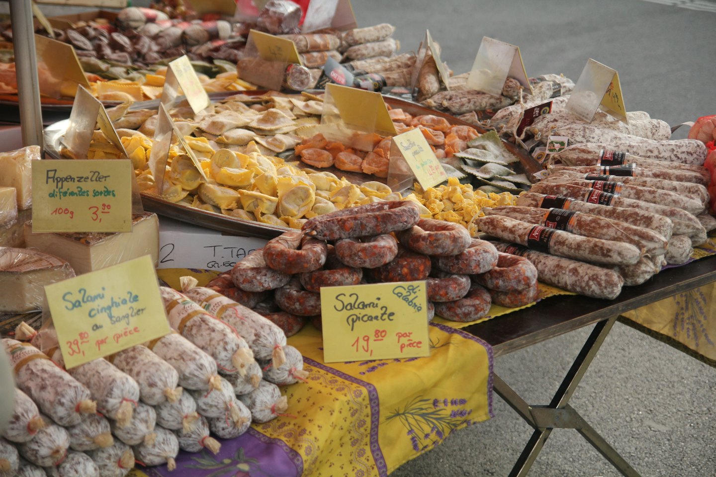 Mercato all'aperto con salumi, pasta e formaggio.