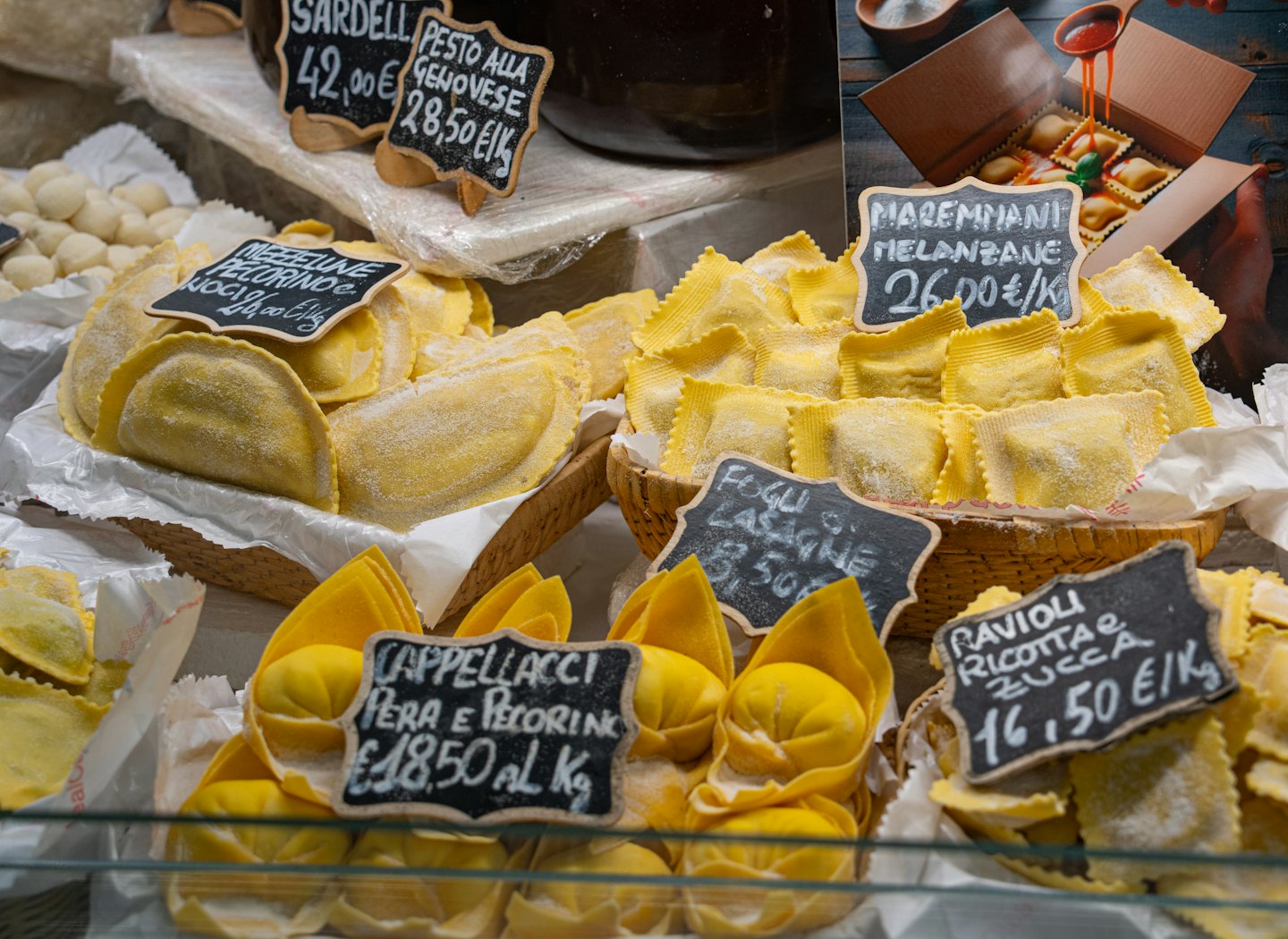 Pasta artigianale italiana disposta su vassoi in un mercato.