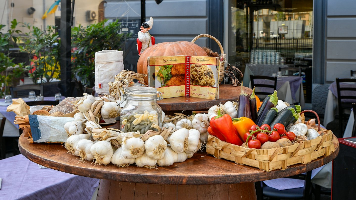 Verdure fresche e cibi italiani disposti su un tavolo di legno.