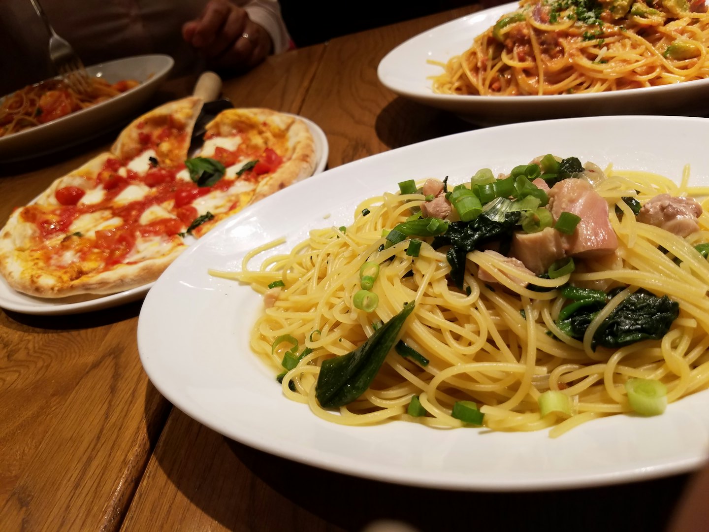 Piatti di pasta italiana e pizza disposti su un tavolo di legno.